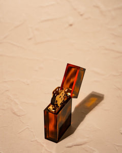 Open Tsubota Pearl Hard Edge lighter in translucent amber finish, flint wheel and brass windguard visible