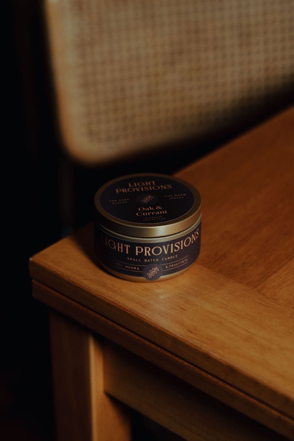 Oak and Currant 4.75 oz travel tin candle with dark label on wooden table