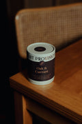 Oak and Currant 9.5 oz ribbed glass tumbler candle with premium paper tube packaging on wooden table