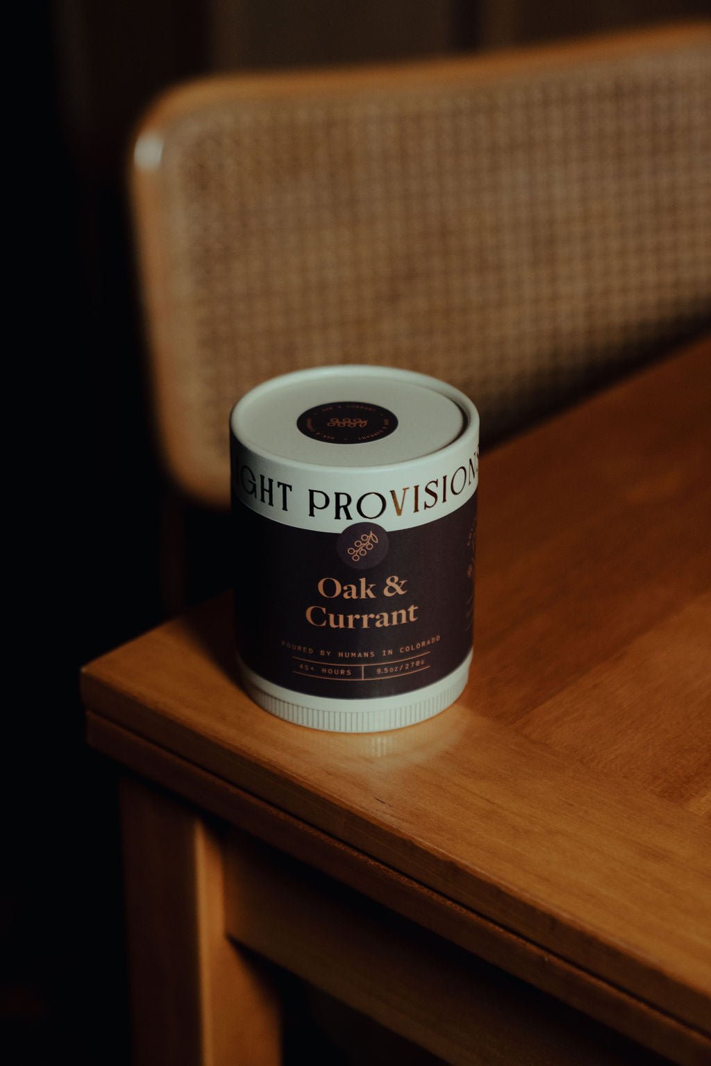 Oak and Currant 9.5 oz ribbed glass tumbler candle with premium paper tube packaging on wooden table