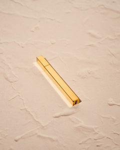 Tsubota Pearl Queue lighter in polished gold finish, photographed for Light Provisions against textured neutral background
