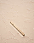 silver toned Queue Lighter by Tsubota Pearl in gold finish on textured beige surface