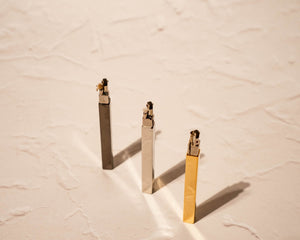 Array of 3 stick lighters: black, silver, gold, standing up with caps off and flint wheels exposed